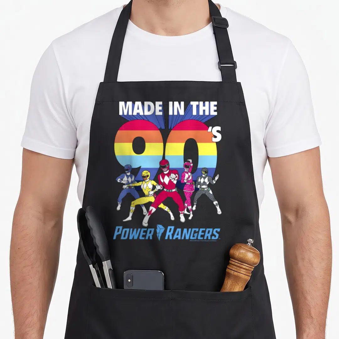 90s stripe apron - Five Power Rangers in red blue yellow pink and black standing before rainbow 90s text — shown on a black cotton canvas apron against a white background