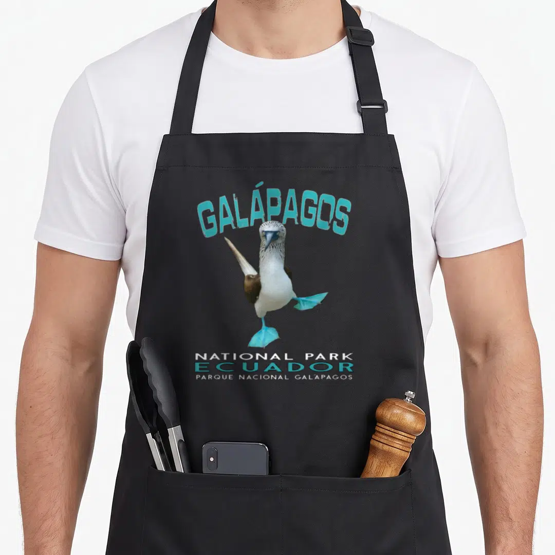 Galapago booby apron - Blue-footed booby with cyan feet and arched Galapagos text — shown on a black cotton canvas apron against a white background
