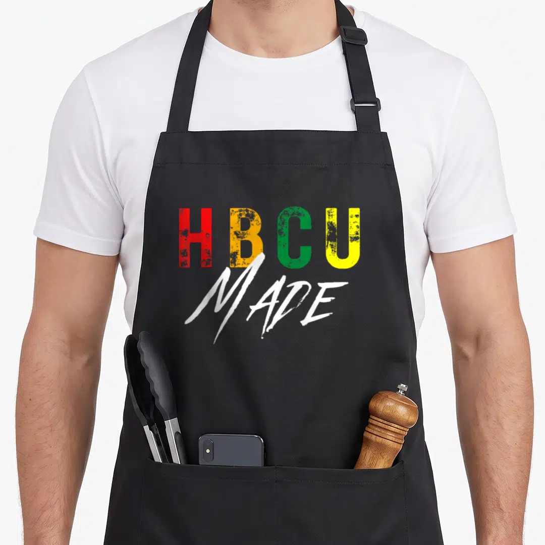 Student historical aprons - HBCU MADE text in red yellow green and white stacked typography — shown on a black cotton canvas apron against a white background
