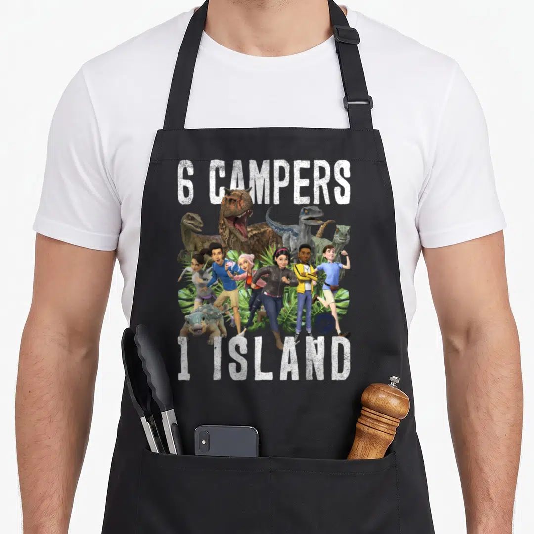 Jurassic kitchen island apron - 6 CAMPERS 1 ISLAND text with six running humans and dinosaurs among tropical leaves — shown on a black cotton canvas apron against a white background