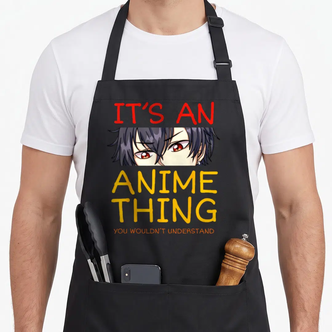 Funny manga anime apron - Anime character eyes with IT'S AN ANIME THING YOU WOULDN'T UNDERSTAND text in red, yellow — shown on a black cotton canvas apron against a white background