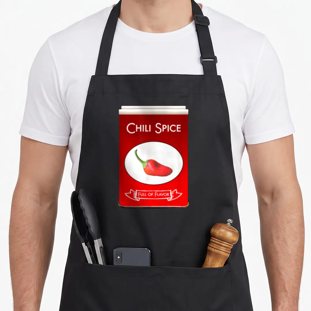 Chili spice apron - Red spice tin graphic with chili pepper and FULL OF FLAVOR text — shown on a black cotton canvas apron against a white background