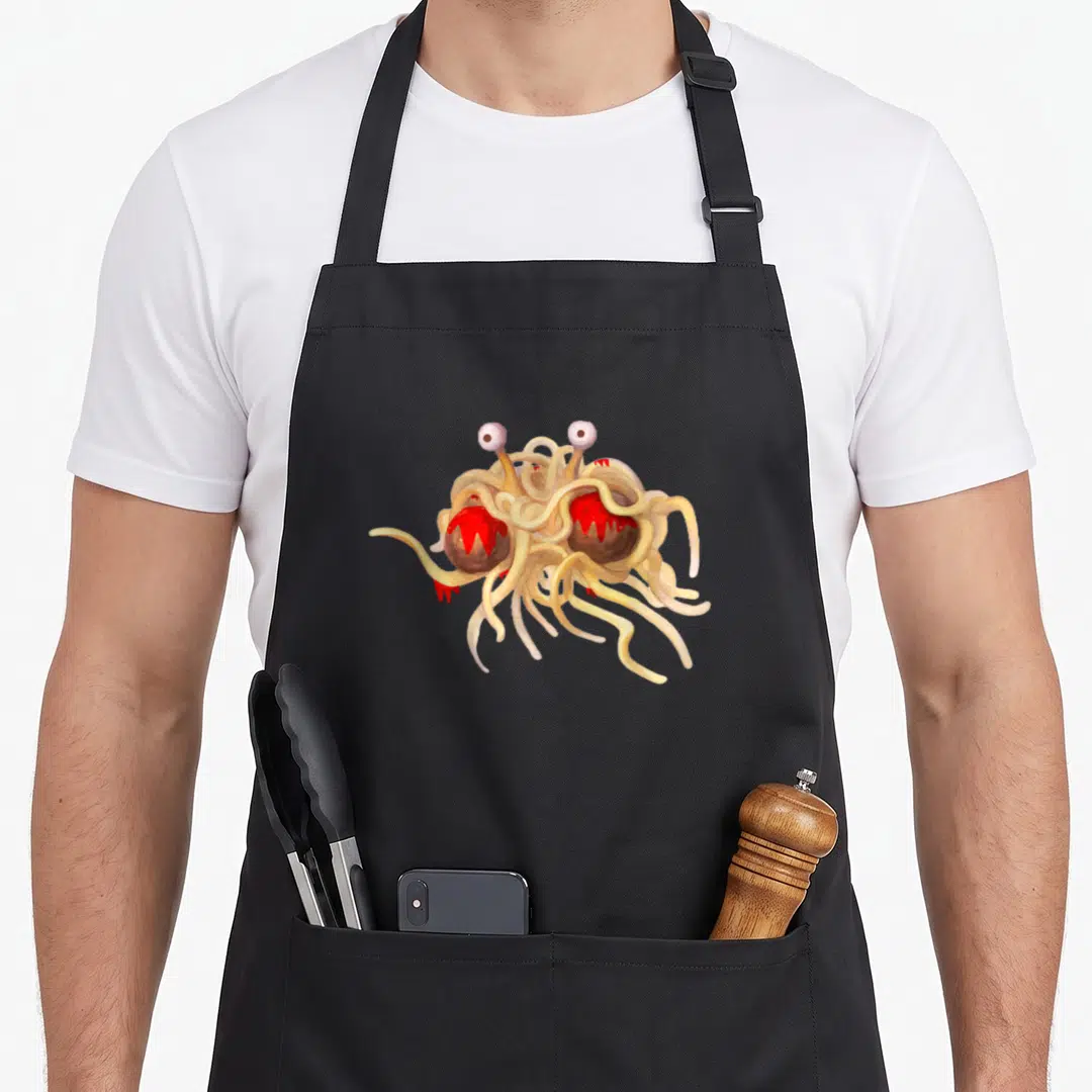 Atheist flying apron - Cartoon monster of noodles and meatballs with two eyes on stalks in beige, red, brown, and white — shown on a black cotton canvas apron against a white background
