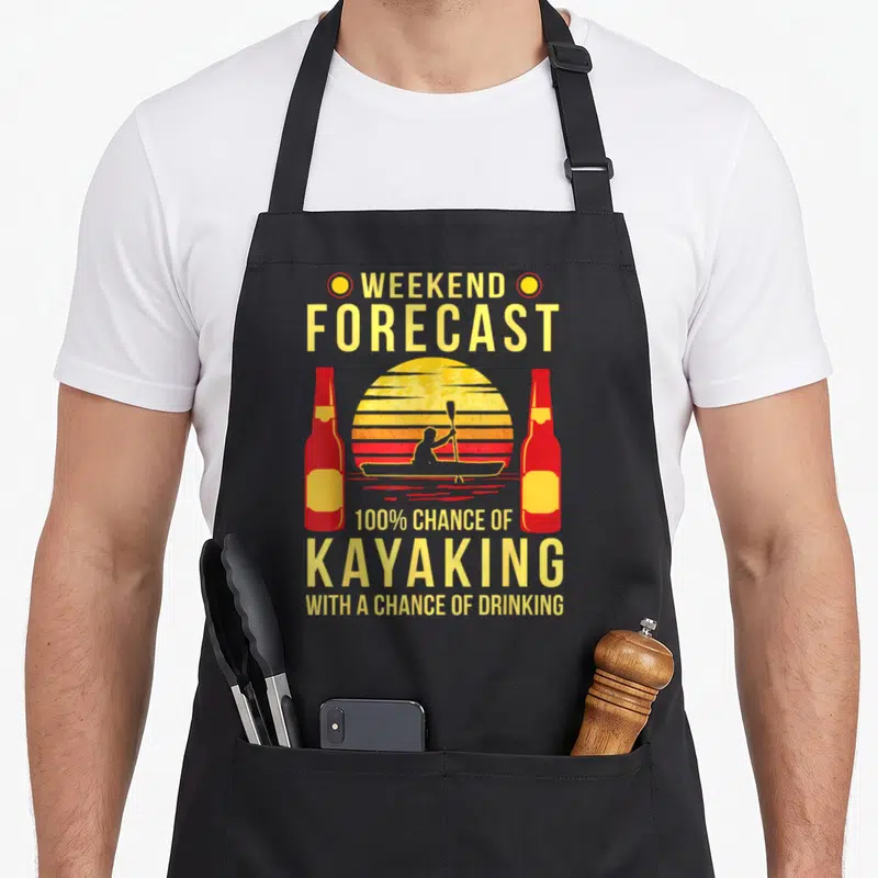 Kayaking beer apron - Retro yellow sun with kayaker silhouette and two red bottles flanking stacked text about weekend — shown on a black cotton canvas apron against a white background