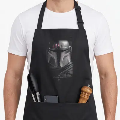 Dark wars new apron - Silver Mandalorian helmet print with THE MANDALORIAN text and small symbol below — shown on a black cotton canvas apron against a white background