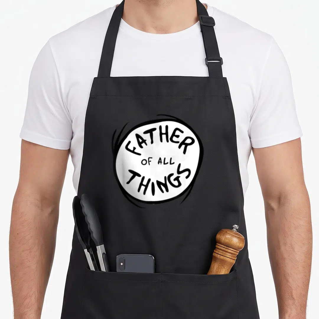 Emblem dad father apron - FATHER OF ALL THINGS text inside a sketchy black circle on white background — shown on a black cotton canvas apron against a white background