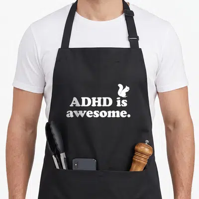 Cute adhd apron - White stacked text reading ADHD is, awesome with a small squirrel silhouette above the word is — shown on a black cotton canvas apron against a white background