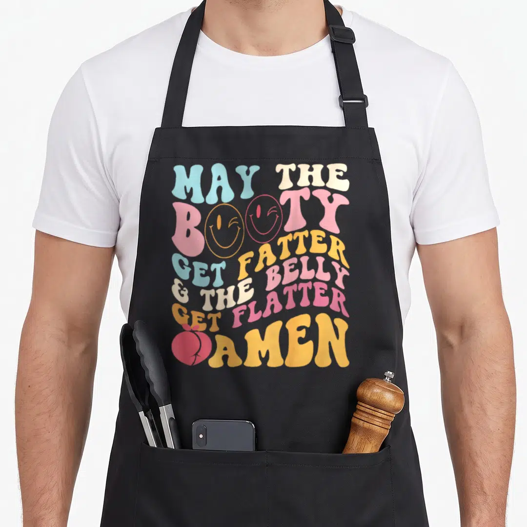 May amen apron - Retro text May The Booty Get Fatter Belly Flatter Amen with smileys and peach icon — shown on a black cotton canvas apron against a white background
