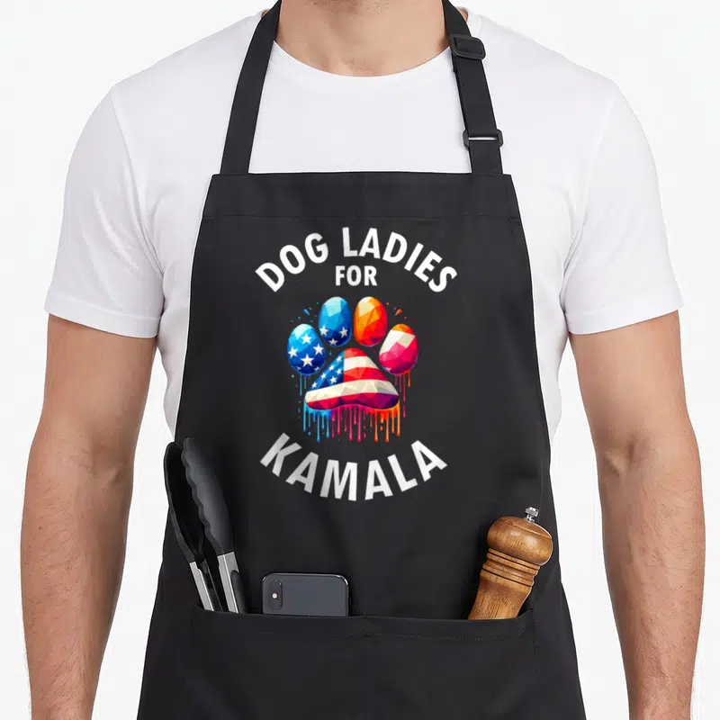 Childless dog apron - Patriotic paw print with DOG LADIES FOR KAMALA text and dripping paint effect — shown on a black cotton canvas apron against a white background