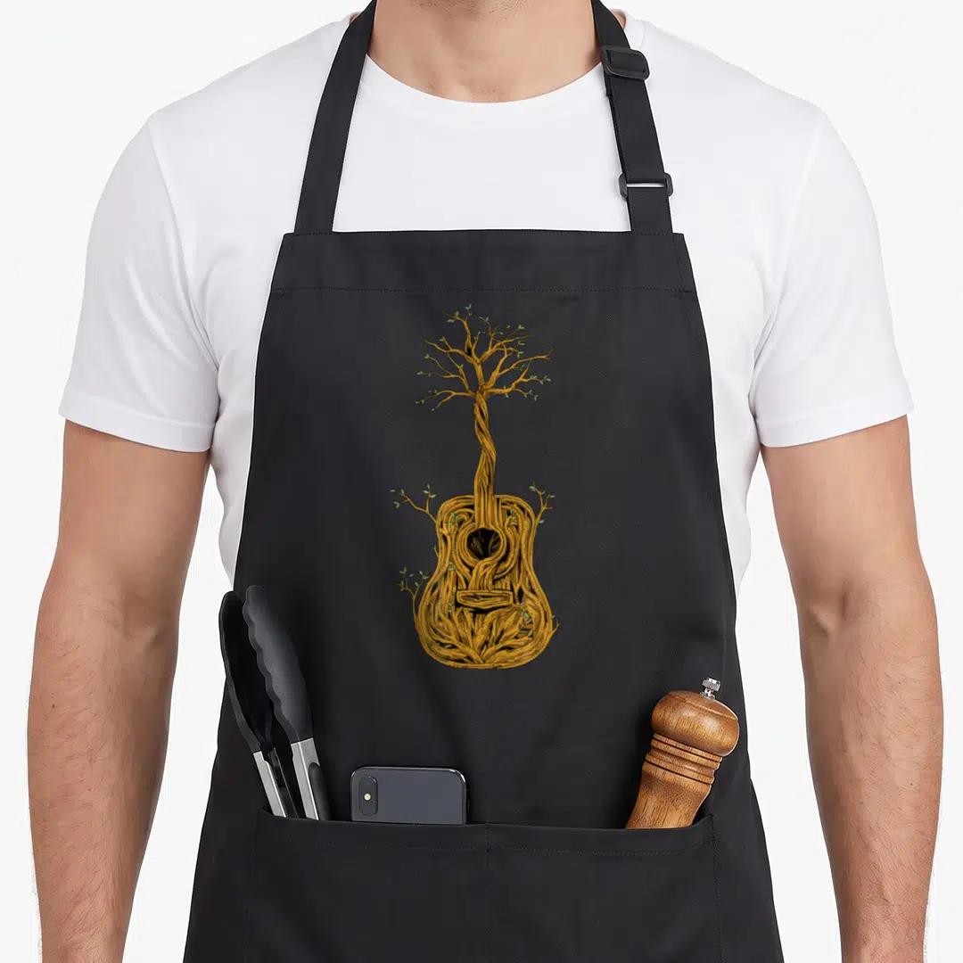 Acoustic tree apron - Guitar body morphs into tree with orange-brown wood and green leaves — shown on a black cotton canvas apron against a white background