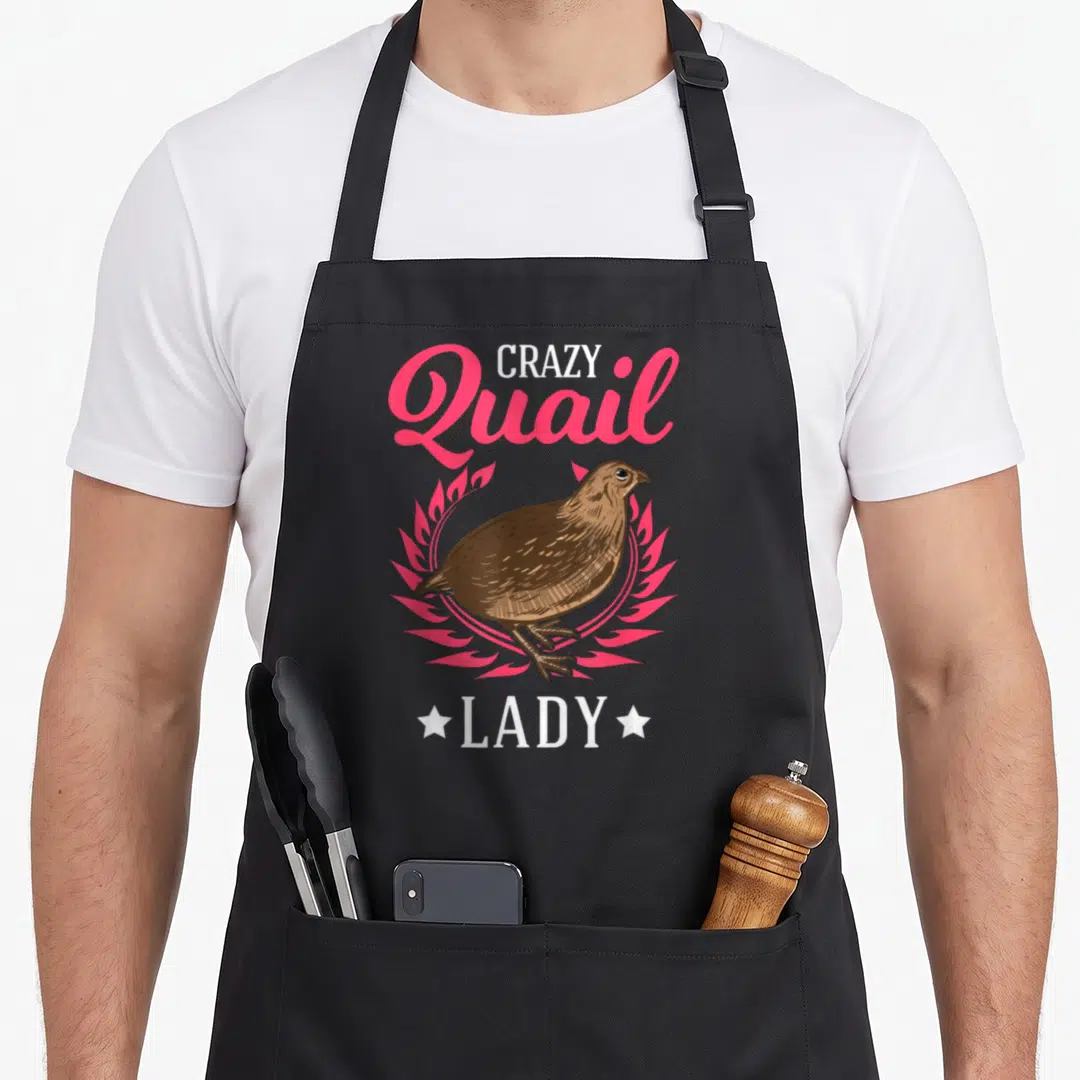 Clothe crazy quail lady apron - Cartoon brown quail in pink wreath with CRAZY Quail LADY text and two white stars — shown on a black cotton canvas apron against a white background