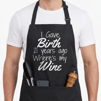21st wine aprons - White stacked text reading I Gave Birth 21 Years Ago Where's my Wine — shown on a black cotton canvas apron against a white background