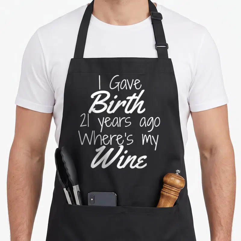 21st wine aprons - White stacked text reading I Gave Birth 21 Years Ago Where's my Wine — shown on a black cotton canvas apron against a white background