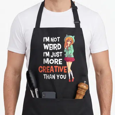 Manga creative apron - Stacked text I'm Not Weird I'm Just More Creative Than You beside anime girl in mint hat — shown on a black cotton canvas apron against a white background
