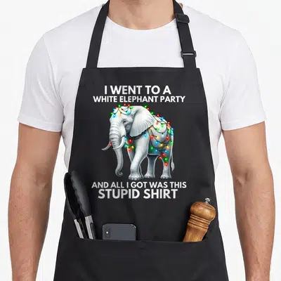 Wrapped elephant print apron - Realistic white elephant wrapped in multicolored lights with sarcastic party text — shown on a black cotton canvas apron against a white background