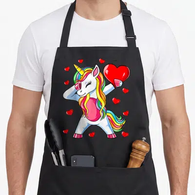 Unicorn valentine apron - Dabbing white unicorn holding large red heart with rainbow mane and scattered smaller hearts — shown on a black cotton canvas apron against a white background