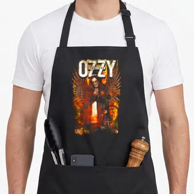 Saint ozzy osbourne apron - Distressed OZZY OSBOURNE text with winged figure amidst orange and yellow fire — shown on a black cotton canvas apron against a white background