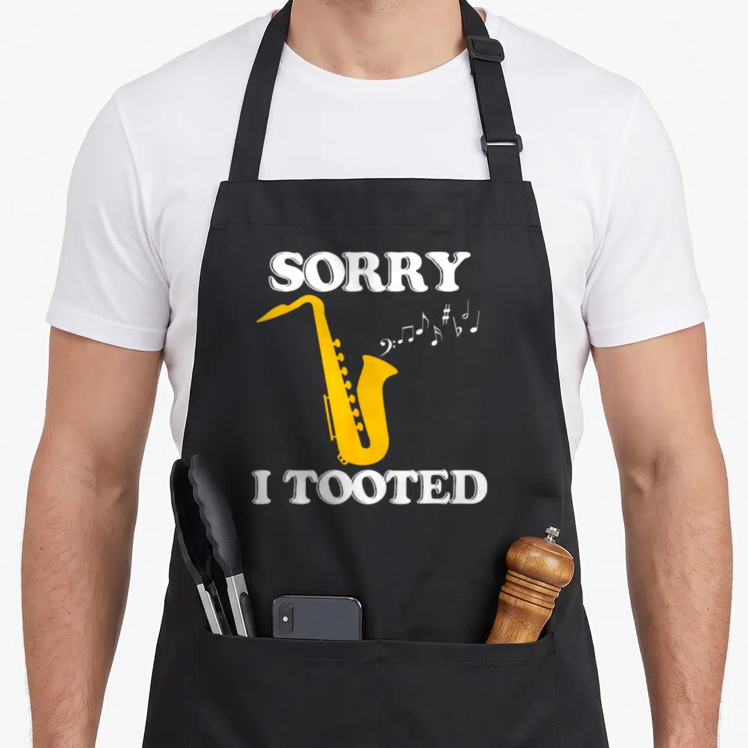 Tooted saxophone apron - Yellow saxophone illustration with white sorry i tooted text and musical notes — shown on a black cotton canvas apron against a white background