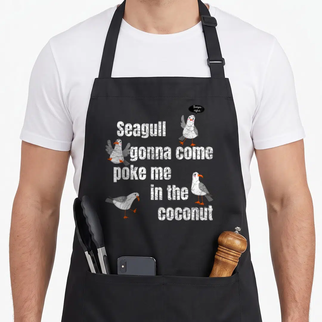 Seagull sea man apron - Four cartoon seagulls surround stacked white text reading Seagull gonna come poke me — shown on a black cotton canvas apron against a white background