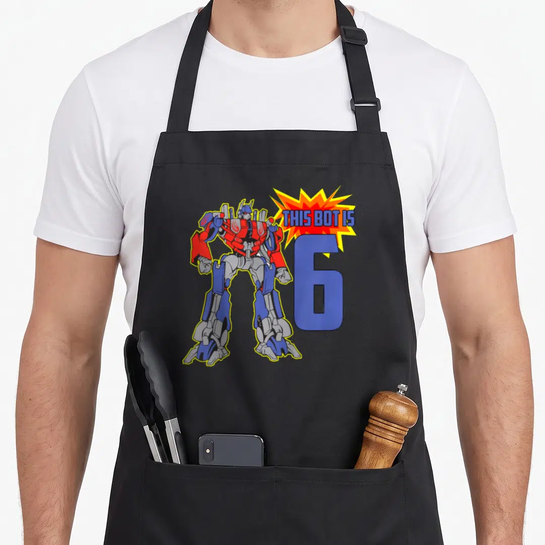 Robot 6th birthday apron - Cartoon robot stands beside large blue number 6 and explosion graphic with text — shown on a black cotton canvas apron against a white background