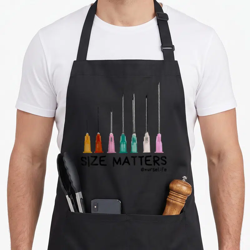 Come nurse apron - Seven increasing size needles above SIZE MATTERS text in black, pink, teal, orange, silver — shown on a black cotton canvas apron against a white background