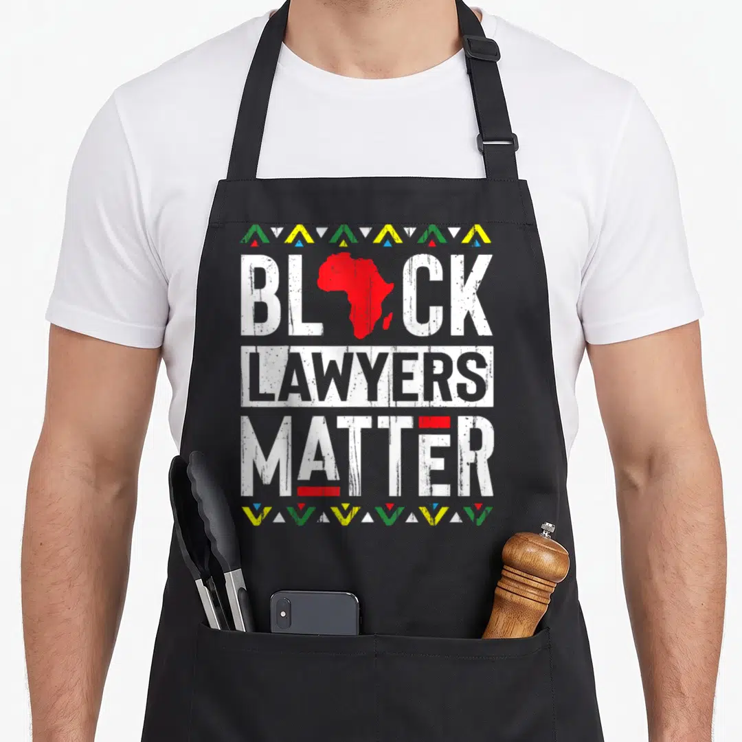 Month lawyer apron - Red Africa map as A in BLACK LAWYERS MATTER, distressed white text, colored triangle borders top — shown on a black cotton canvas apron against a white background
