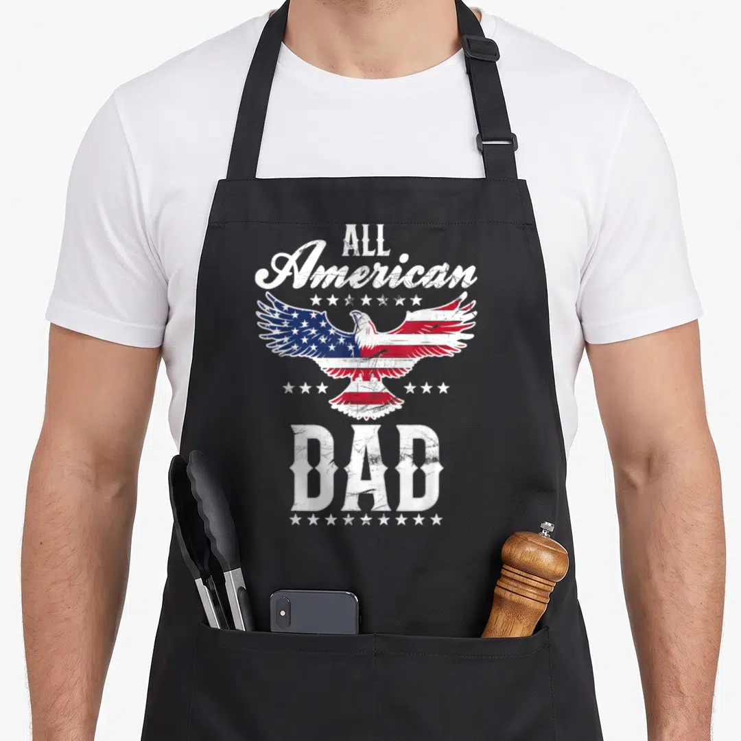 Eagle father day apron - Distressed eagle with American flag wings surrounded by stars and All American Dad text — shown on a black cotton canvas apron against a white background