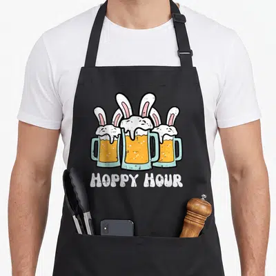 Hour easter bunny aprons - Three beer mugs with rabbit ears and HOPPY HOUR text in yellow blue white pink — shown on a black cotton canvas apron against a white background