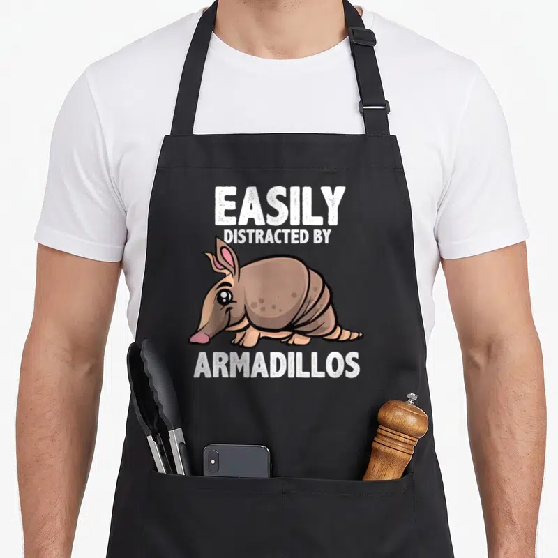 Armadillo lover easily apron - Cartoon brown armadillo with pink nose below white text EASILY DISTRACTED BY ARMADILLOS — shown on a black cotton canvas apron against a white background