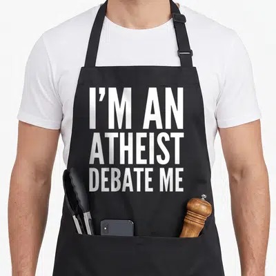 Atheist adult birthday apron - White stacked text reading I'M AN ATHEIST DEBATE ME on black fabric — shown on a black cotton canvas apron against a white background
