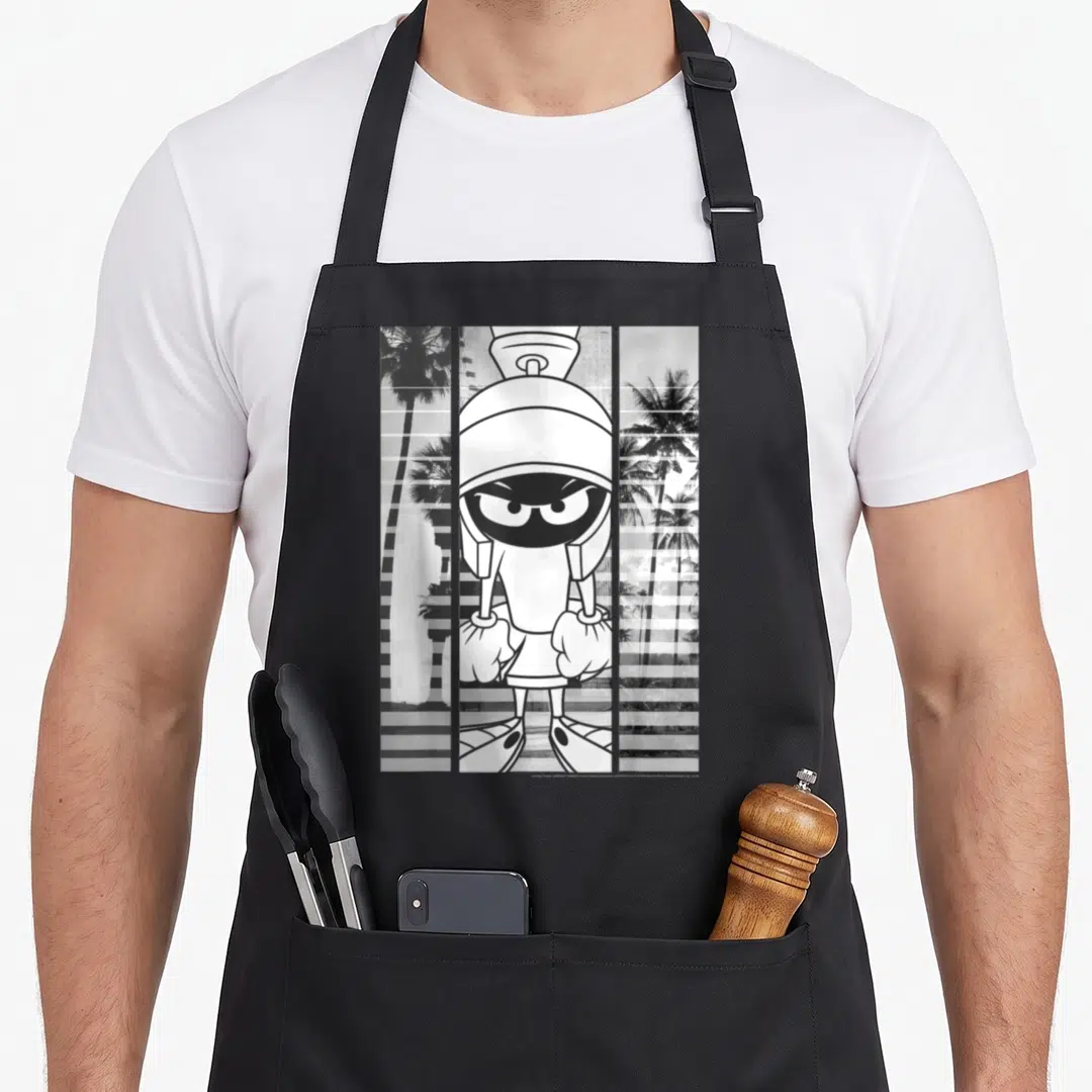 Marvin lined apron - Central cartoon character flanked by palm tree panels with horizontal stripe overlay in monochrome — shown on a black cotton canvas apron against a white background