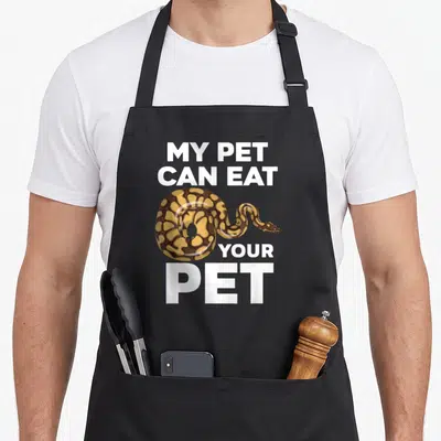 Eat pet apron - Realistic snake illustration with white text reading MY PET CAN EAT YOUR PET — shown on a black cotton canvas apron against a white background