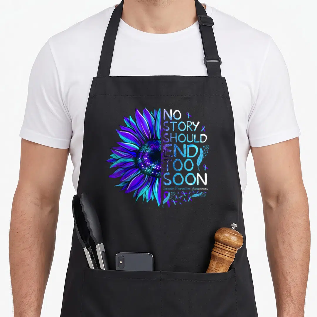 Suicide story of the apron - Split sunflower in blue and purple with NO STORY SHOULD END TOO SOON text and ribbons — shown on a black cotton canvas apron against a white background