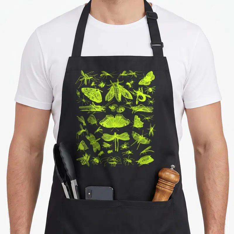 Collection entomologist apron - lime green line art of moths beetles dragonflies and spiders scattered across a grey — shown on a black cotton canvas apron against a white background