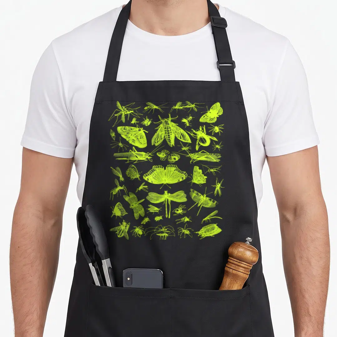 Collection entomologist apron - lime green line art of moths beetles dragonflies and spiders scattered across a grey — shown on a black cotton canvas apron against a white background