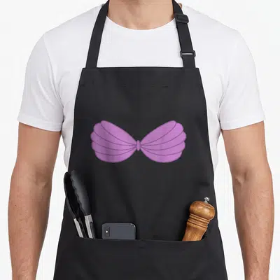 Mermaid cartoon apron - Purple cartoon seashell bra graphic centered on apron front — shown on a black cotton canvas apron against a white background