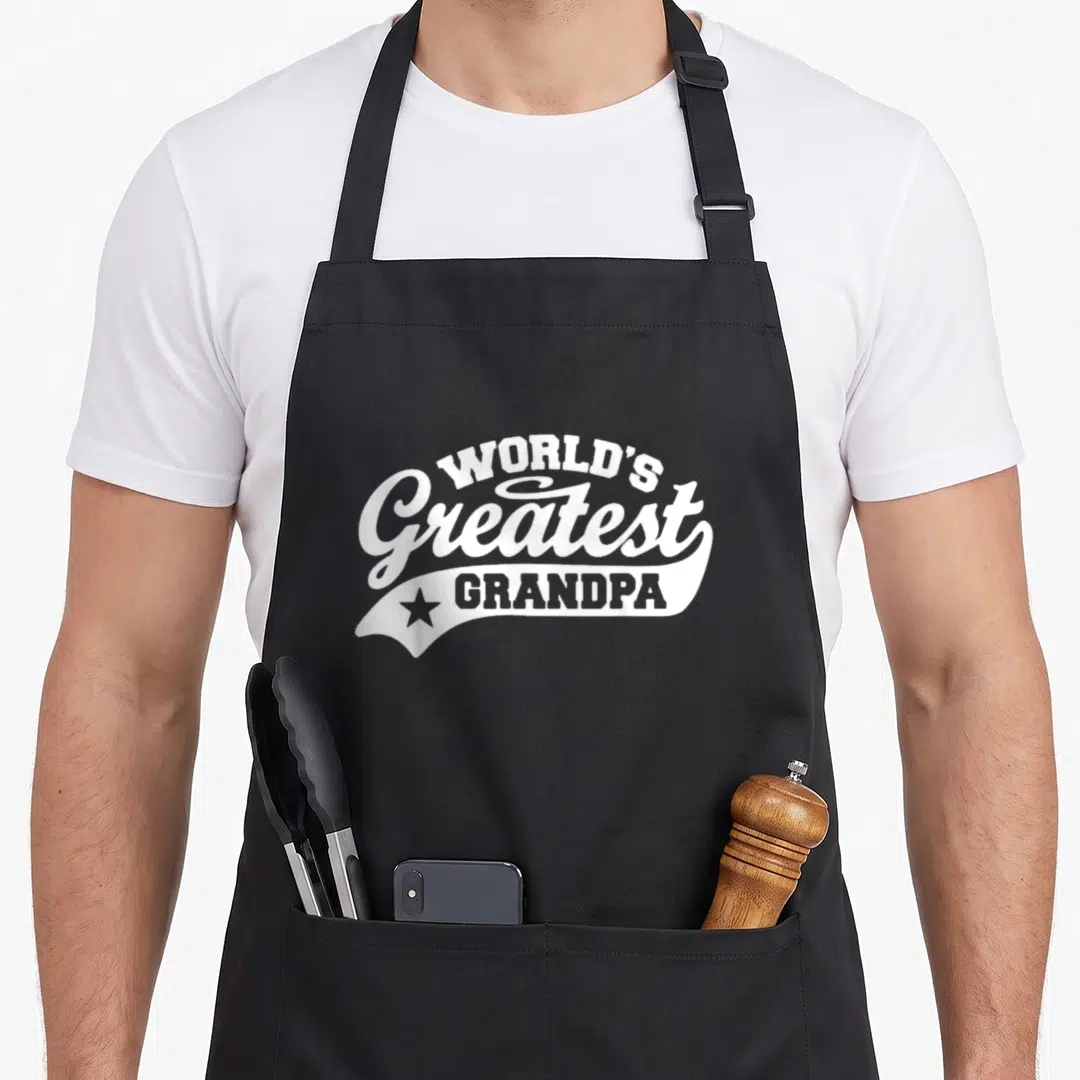 Grandpa father worlds greatest dad apron - White text reading WORLD'S Greatest GRANDPA stacked with a star banner — shown on a black cotton canvas apron against a white background
