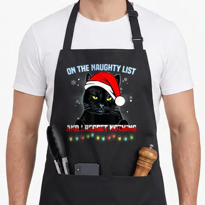 List christmas apron - Black cat in red Santa hat with text ON THE NAUGHTY LIST AND I REGRET NOTHING and colorful lights — shown on a black cotton canvas apron against a white background