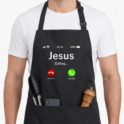 Calling christian apron - Grey smartphone screen graphic with Jesus calling text and red and green call buttons — shown on a black cotton canvas apron against a white background