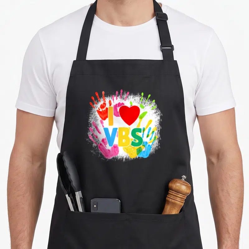 School handprint apron - I VBS text with red heart and colorful handprints on white splatter background — shown on a black cotton canvas apron against a white background