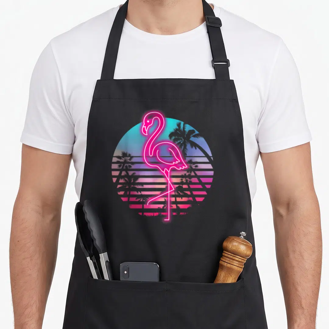 Zoo flamingo apron - Neon pink flamingo outline over retro gradient circle with palm trees and stripes — shown on a black cotton canvas apron against a white background