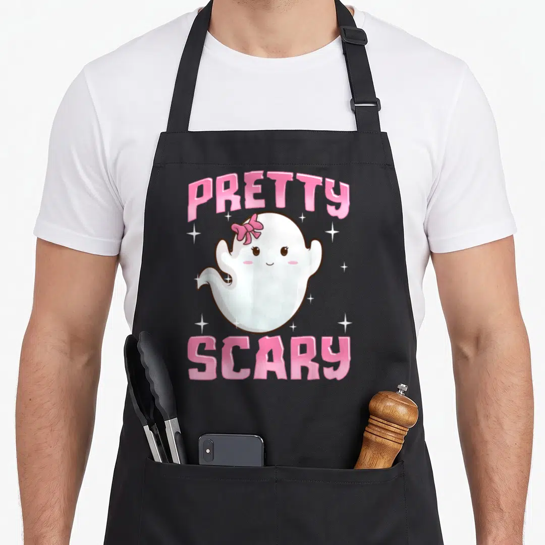 Pretty halloween apron - White ghost with pink bow surrounded by stars under arched pink PRETTY SCARY text — shown on a black cotton canvas apron against a white background