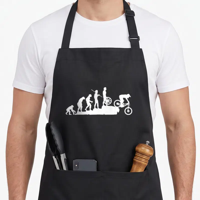 Evolution bike apron - Six white silhouettes showing human evolution ending with a mountain biker riding downhill — shown on a black cotton canvas apron against a white background