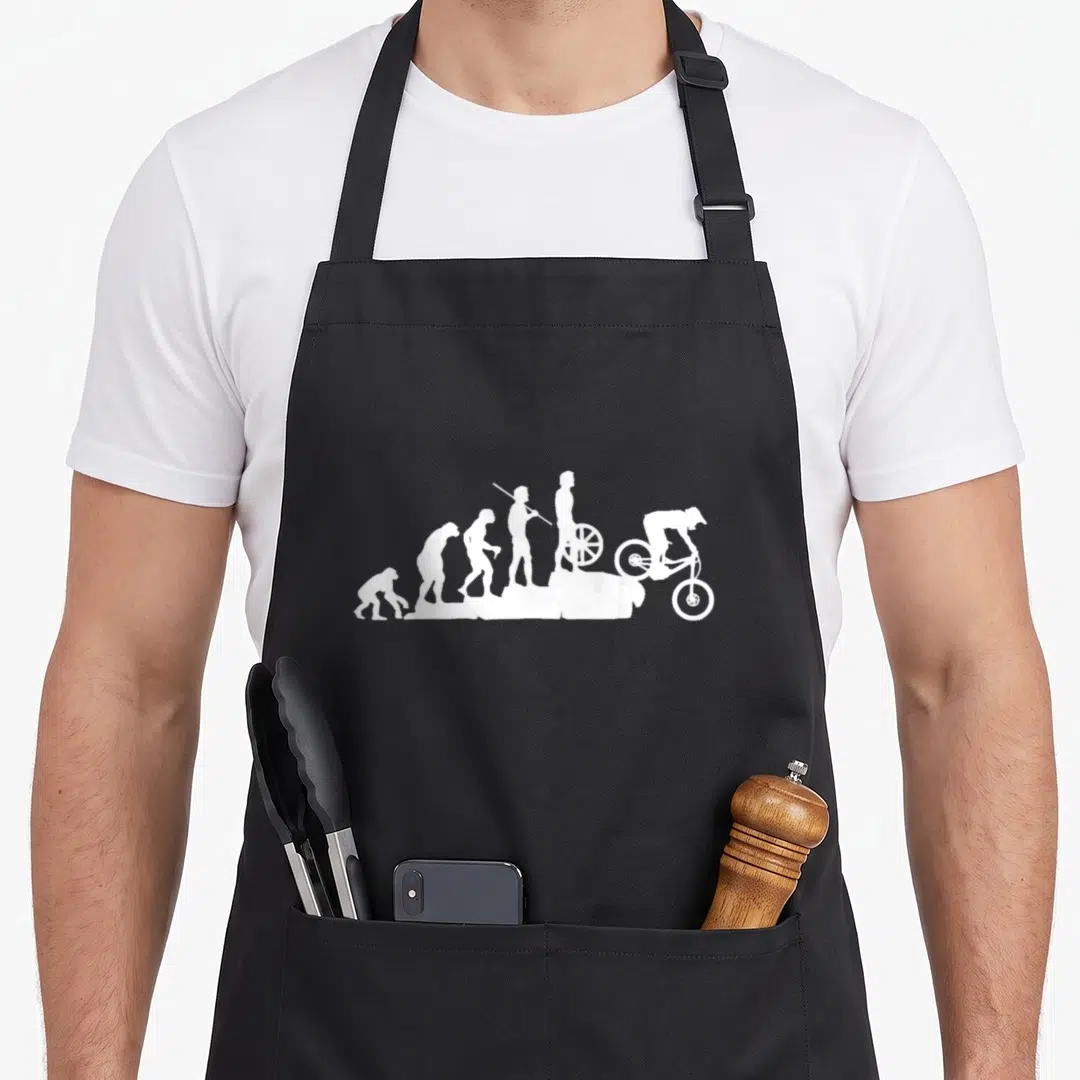 Evolution bike apron - Six white silhouettes showing human evolution ending with a mountain biker riding downhill — shown on a black cotton canvas apron against a white background