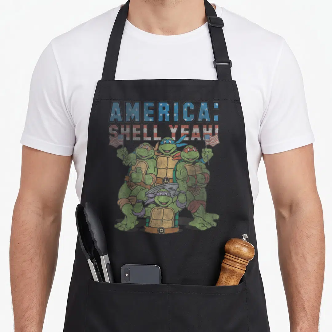 Shell teenage mutant ninja apron - Four turtles holding flags under stacked text with star and stripe patterns inside — shown on a black cotton canvas apron against a white background