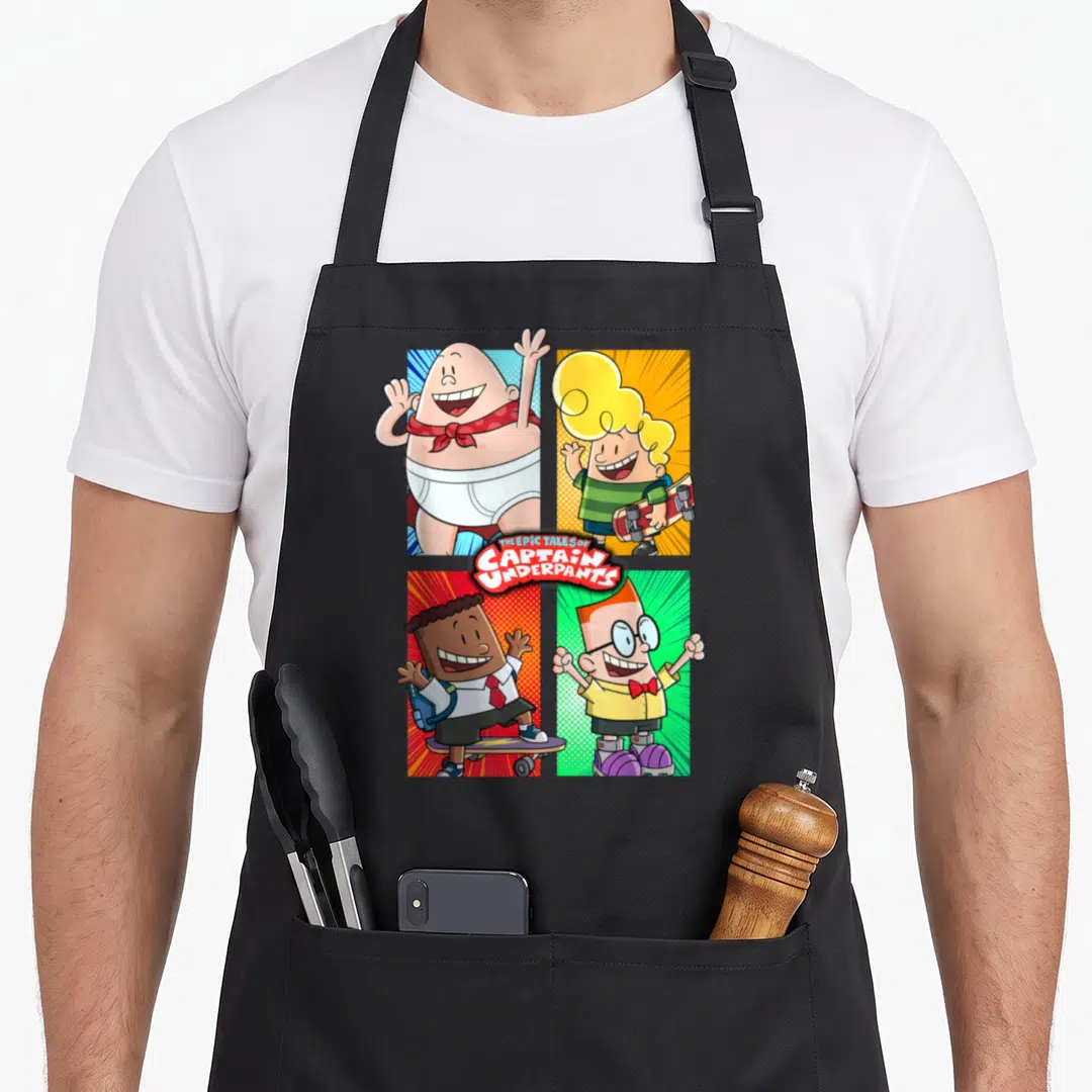 Underpant friends apron - Captain Underpants four panel grid with red yellow blue green backgrounds and central title — shown on a black cotton canvas apron against a white background
