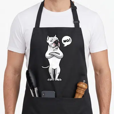 Argentine dog apron - White cartoon dog with arms crossed and NO! speech bubble in black and pink — shown on a black cotton canvas apron against a white background