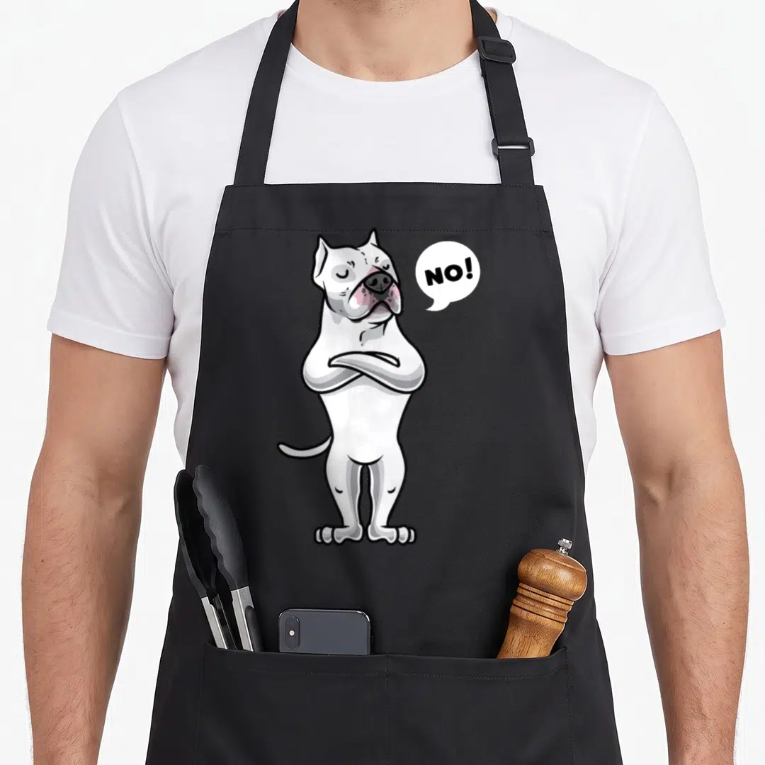 Argentine dog apron - White cartoon dog with arms crossed and NO! speech bubble in black and pink — shown on a black cotton canvas apron against a white background