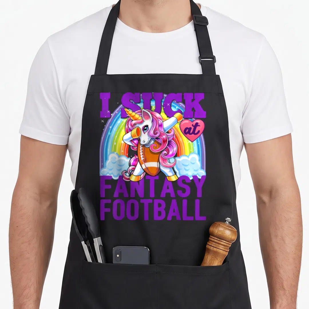 Unicorn football apron - Dabbing unicorn holding football in front of rainbow with purple text — shown on a black cotton canvas apron against a white background