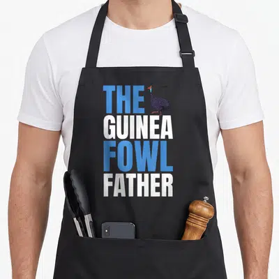 Guinea chicken apron - Stacked blue and white text reading The Guinea Fowl Father with a bird illustration — shown on a black cotton canvas apron against a white background